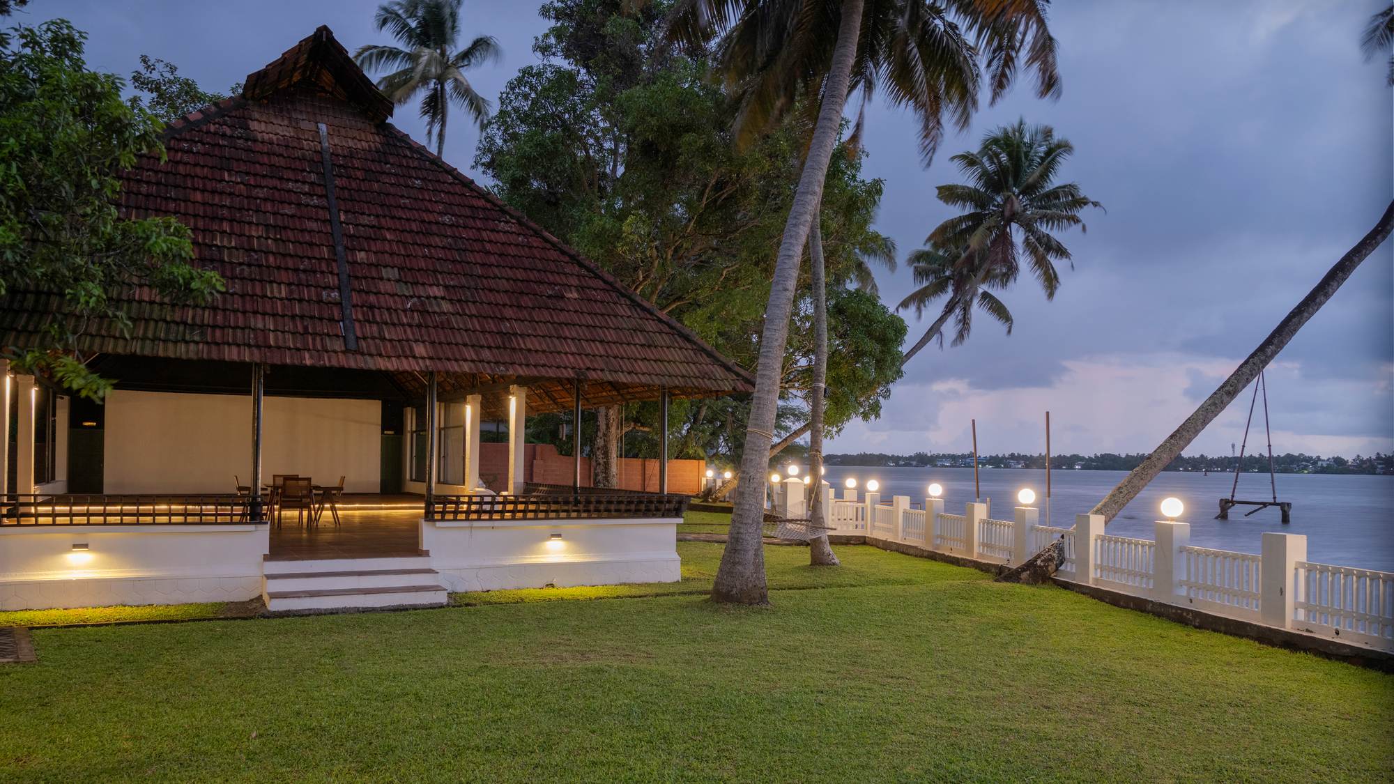 Theeram Backwaters at dusk, the pandal lit and the grounds lush around it