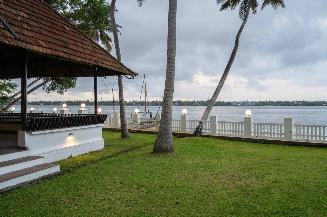 The pandal exterior at dusk with palms and backwater beyond